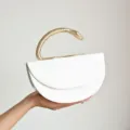 Detailansicht der weißen Schlangenmuster Abendtasche mit goldenem Schlangengriff. - Weiß