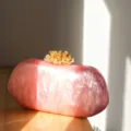 Nahaufnahme der eleganten rosa Acryl-Abendtasche mit goldenem Korallen-Verschlussdetail. - Marmor Rosa