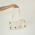 Nahaufnahme der beige Leder-Umhängetasche mit metallischen Ösenringen und nieten Akzenten. - Weiß (Klein)