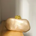 Detailsicht marmorierte Hartschalen Abendtasche in Champagner mit goldenem Korallenverschluss. - Flüssiges Gold