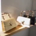 Modische einfarbige kleine Handtasche mit einzigartigem unregelmäßigem Metallgriff und Verschluss. - Gold