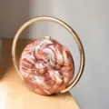 Exquisite acrylic round evening bag with marble pattern and striking gold ring handle detail. - Caramel color
