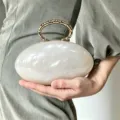 Nahaufnahme der eleganten Marmor-Textur Ovale Clutch Tasche mit goldenem Metall-Ringgriff. - Weiß