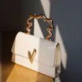 Schicke kleine Handtasche mit unregelmäßigem Metallgriff und modernem Verschluss, stilvoll. - Weiß