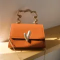 Caramel trendy small square bag detail showing irregular metallic handle and heart clasp. - Tan