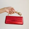 Detailansicht der roten metallischen Krokodilmuster Abendtasche mit goldenem Tulpenhenkel. - S / Rot