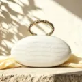French luxury oval clutch bag with PU texture and elegant metal ring handle for evening parties. - White