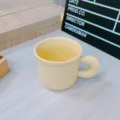 Cream ceramic coffee mug with round handle, cute ins style tableware detail view. - Chubby Handle Mug