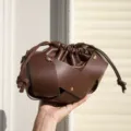 Close up of brown soft leather drawstring crossbody bag with unique knot strap and pleated detail. - Coffee