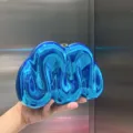 Nahaufnahme der glänzenden metallisch blauen Acryl Abendtasche mit detailierter Textur. - Blau