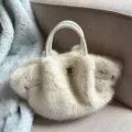 Detailaufnahme der flauschigen Cremefarbigen Plüschtasche mit edlem Verschluss im Winter. - Weiß