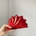 Nahaufnahme der glänzenden roten Acryl-Muschel-Clutch mit exquisiter Oberflächentextur. - Galvanisiertes Rot