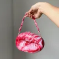 Nahaufnahme der rosafarbenen und weißen Acryl-Abendtasche mit Perlenarmbanddetail. - Fuchsia