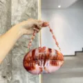 Stunning gradient acrylic evening bag with unique shell shape and chic beaded chain strap. - Amber