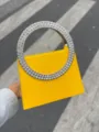 Detailansicht der luxuriösen gelben Abendtasche mit funkelndem Strass-Kreisgriff. - Gelb
