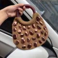 Stylish brown canvas handbag featuring wooden round handles and glossy metallic pebble studs. - Brown