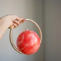 Rote marmorierte kugelförmige Abendtasche mit goldem Ringgriff, elegante Luxus-Clutch Detail. - Fluid Wassermelone Rot