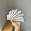 Nahaufnahme der eleganten muscheltexturierten Abendtasche mit einzigartigem geschwungenem Design. - Cremeweiß