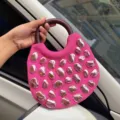 Rosa Stoff Handtasche mit rundem dunklem Griff und einzigartigen metallischen Steinen. - Fuchsia
