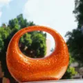 Close up of sparkling orange sequin crescent bag showcasing glittering texture details. - Orange