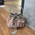 Elegante bolso tipo cubo de perlas y estrás con asa de anillo metálico y borlas. - Circonita de Colores