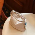 Nahaufnahme der luxuriösen Samtabendtasche mit Perlen-Strass-Griff und bunten Kristallen. - Champagner