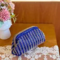 Close-up detail of a luxurious blue rhinestone evening clutch bag with sparkling crystal grid pattern. - Blue