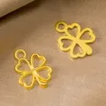 Detail shot of golden hollow four-leaf clover alloy pendant, perfect for DIY jewelry making. - 17x13mm / Gold