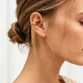 Nahaufnahme des goldenen Edelstahl-Ohrrings mit langen Kettenquasten im minimalistischen Stil. - Gold