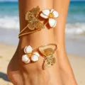 Close-up van een vergulde enkelband met holle vlinders en witte emaille bloem charms. - Vlinder Bloem / Wit