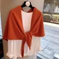 Detalle de cerca del acogedor chal de lana de punto naranja combinado con la parte superior. - Naranja