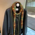 Primer plano de bufanda estrecha de punto a rayas marrones y verdes sobre chaqueta de cuero. - Patchwork Verde Militar