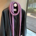 Close-up detail of the purple knitted long skinny scarf draped on black leather jacket. - Light Purple