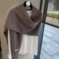 Vista detallada de un elegante chal de punto marrón sobre camisa blanca y suave. - Café / 220x55cm