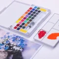 Close-up van draagbare vaste aquarelverfset met kleurrijke napjes en waterpenseel voor kunst. - 36 Kleuren