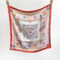 Detailed view of women's floral square silk scarf with geometric border and elegant design. - Orange