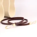 Detailansicht des schmalen braunen Damenlederguertels mit eleganter goldener Haken-Schnalle. - Kaffeebraun