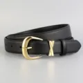 Detail shot of a black genuine leather women's belt with gold pin buckle and X metal loop. - Black