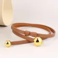 Close-up detail of brown leather women thin belt with shiny gold spherical buckle decoration - 100cm / Brown
