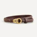 Detail shot of slim dark brown leather belt featuring elegant gold-tone interlocking buckle. - Coffee