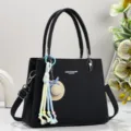Elegante schwarze Ledertasche mit charmantem Anhänger, geräumiger Innenbereich für den Alltag. - Schwarz