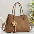 Detailed view of brown textured women handbag with elegant flower charm and metal hardware. - Brown