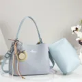 Light blue textured shoulder bag detail featuring charming straw hat charm and matching pouch. - Blue