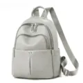 Detail du sac a dos en cuir gris avec poches zippees sur le devant et bretelles reglables. - Gris