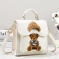 Close-up detail of white PU leather handbag featuring cute 3D teddy bear embroidery patch. - Off White
