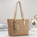 Vista dettagliata della classica borsa kaki con doppi manici e ciondolo intrecciato decorativo. - Cachi