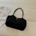 Black minimalist tote shoulder bag detail, showcasing soft fabric and a chic gold metal clasp. - Black