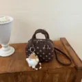Detail view of the brown polka dot bowling shoulder bag with a cute plush charm pendant. - With Pendant / Coffee