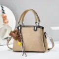 Stilvolle beige Damen Handtasche mit Henkel, schicken Anhängern und Schultergurt. - Aprikose