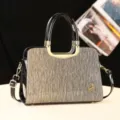 Sac à main élégant pour femme avec design structuré, poignées en métal et bandoulière. - Or